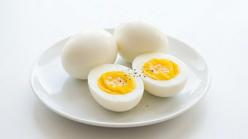view of perfectly cooked hard-boiled eggs, some sliced in half to show creamy yellow yolks, served on a white plate
